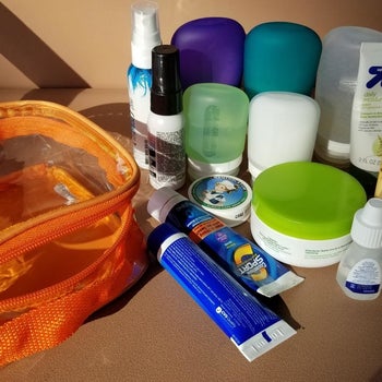 a reviewer photo of lots of toiletries sitting next to an orange bag with a transparent front