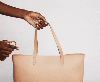 a gif of a model attaching the luggage tag to a tote and clipping a wide--brim hat to the luggage tag