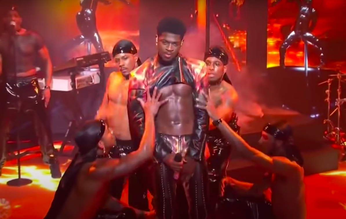 wearing a very cropped top and tight pants, the rapper keeps his front covered while the dancers move around him