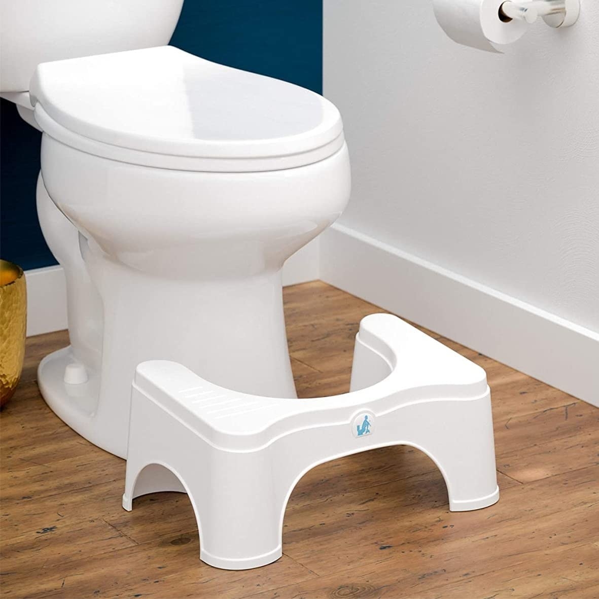 The Squatty Potty stool set in front of a toilet with the lid closed