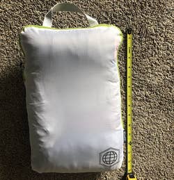a reviewer photo of the shirts packed in a compression cube next to a measuring tape that reads 