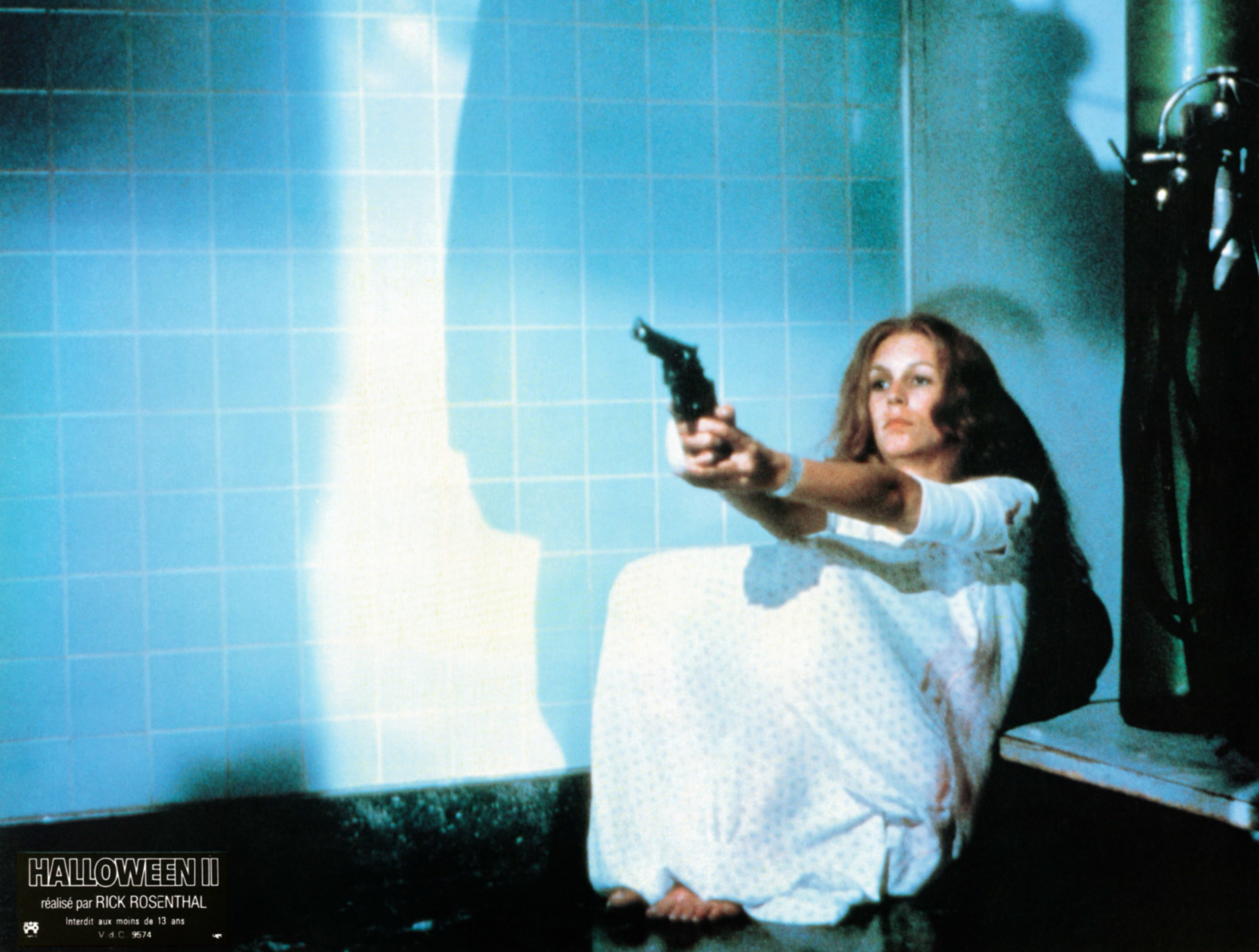 Laurie in a hospital gown pointing a gun