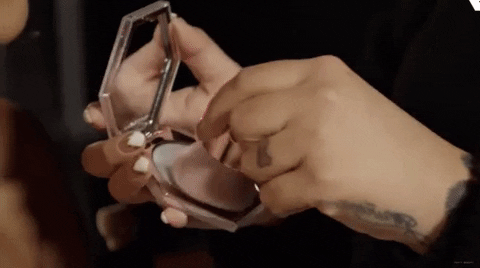 a gif of a makeup artist applying the