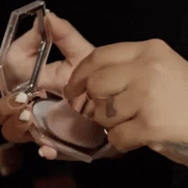 a gif of a makeup artist applying the