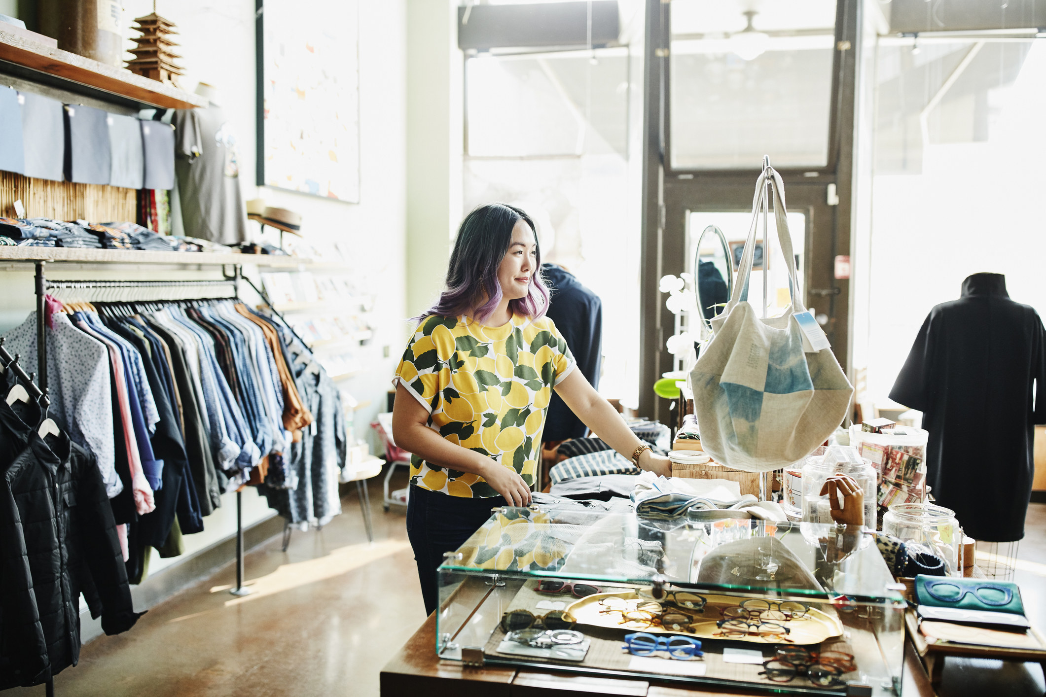 Smiling shopkeeper organizing display in boutique