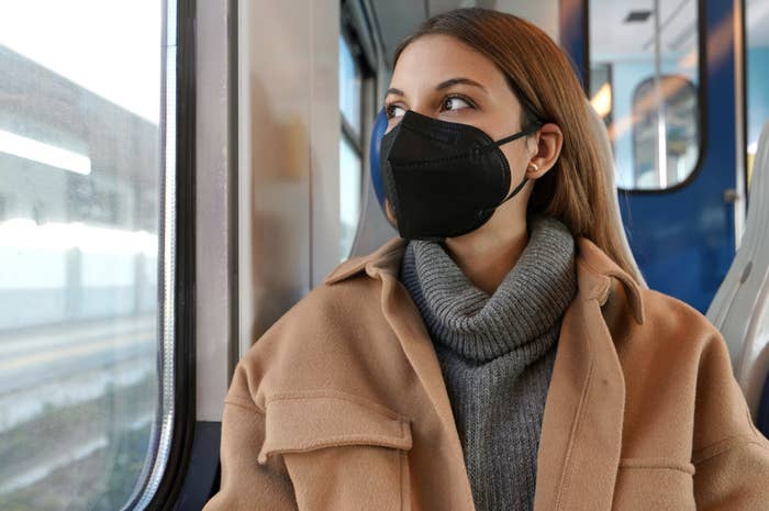 Person sits on train with mask