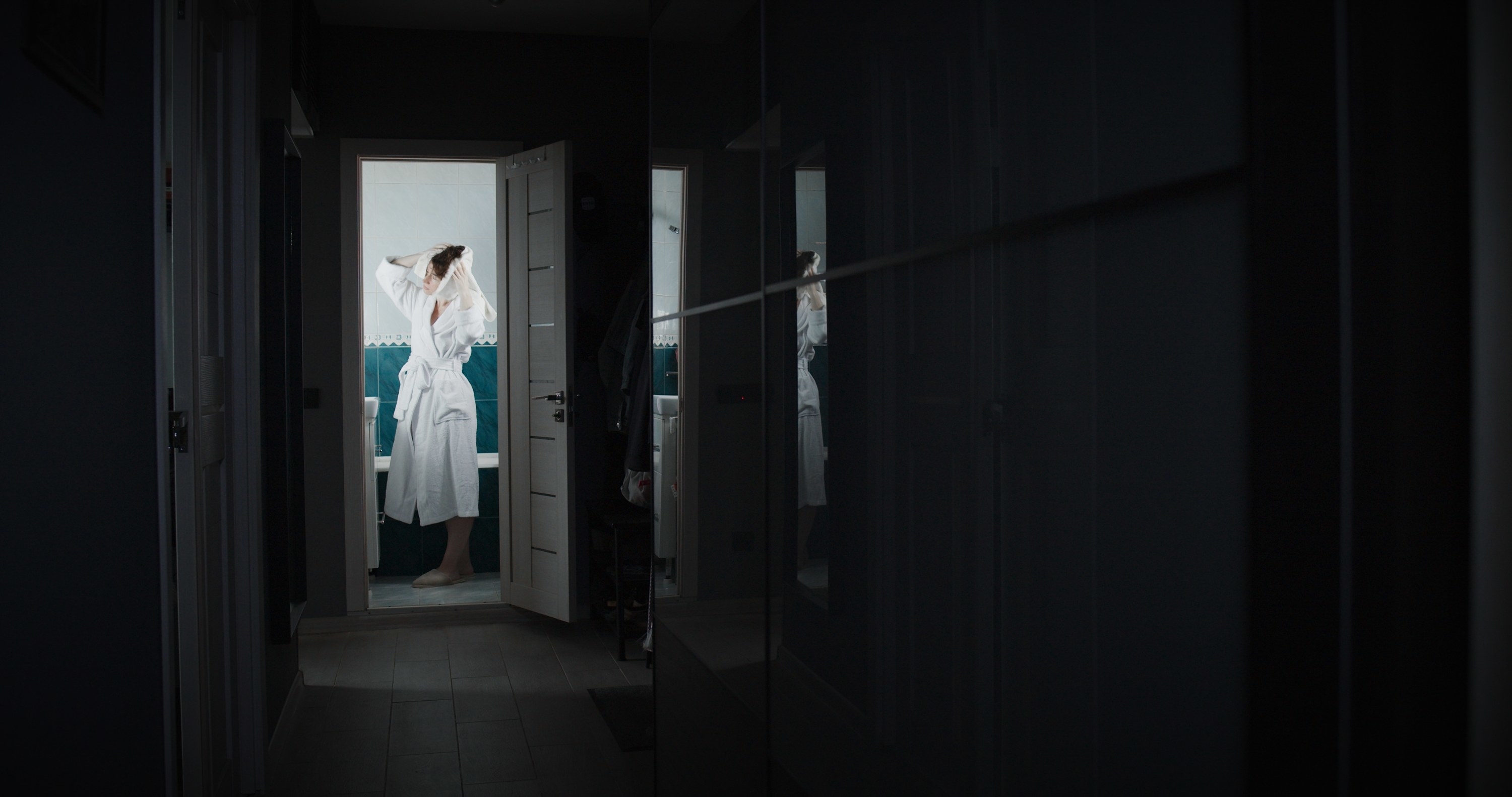 A woman in a robe with. towel around her head after a shower