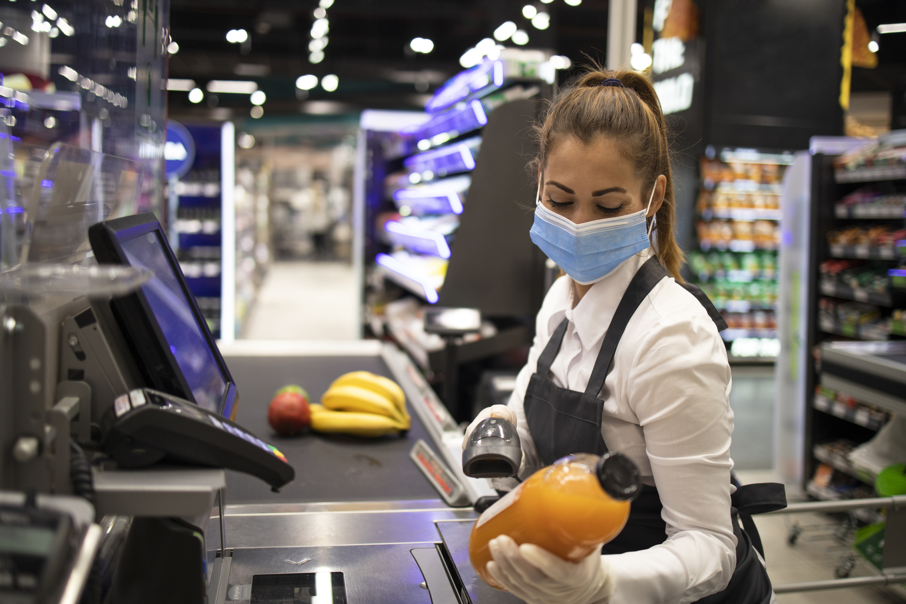 Masked cashier working in a grocery store during the pandemic