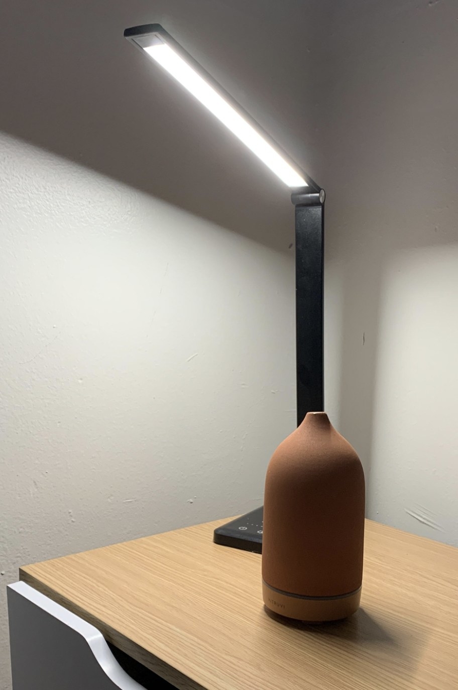 reviewer photo of the lamp in black on a nightstand with an oil diffuser