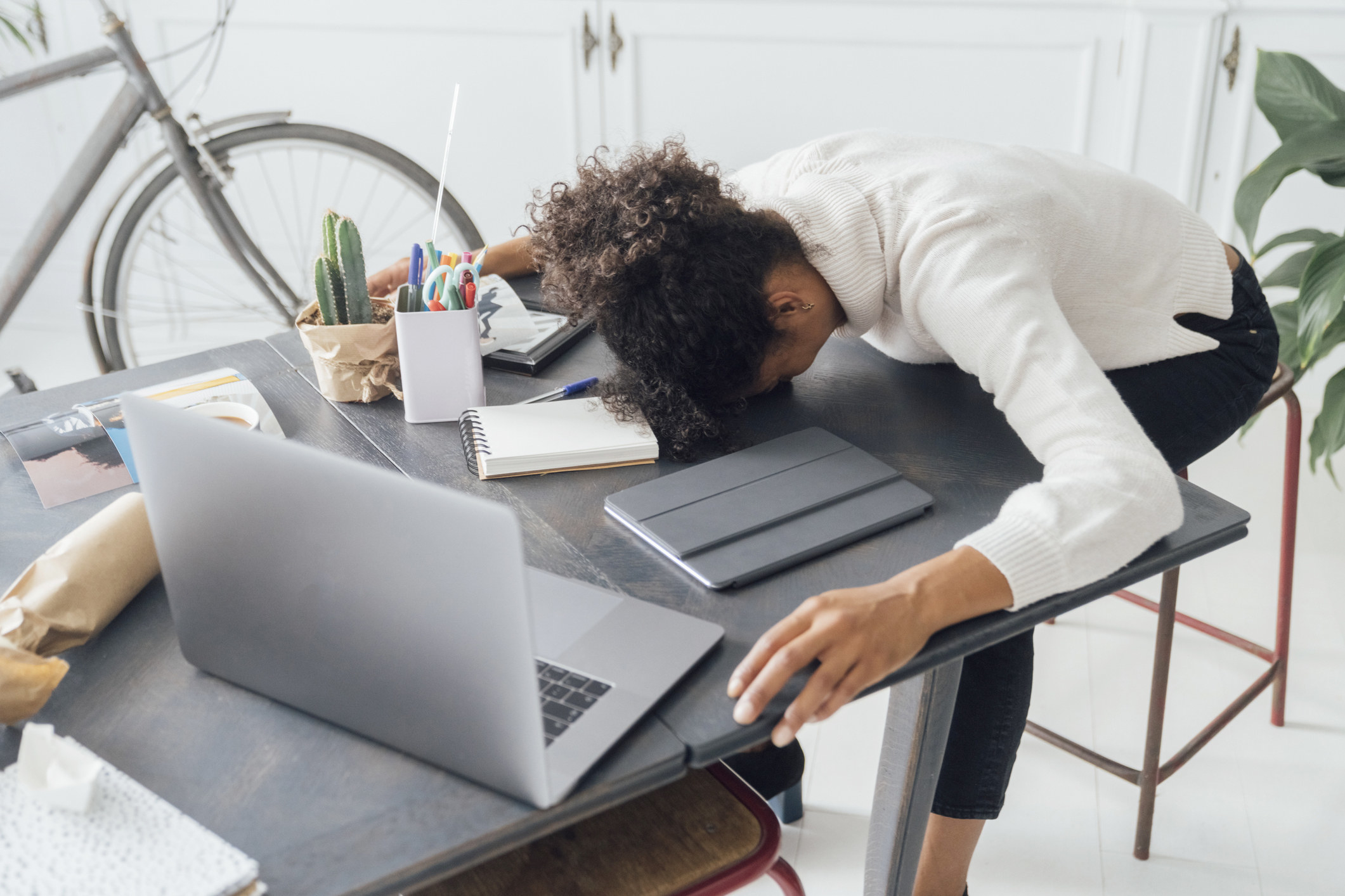 A tired worker putting her head down at her desk
