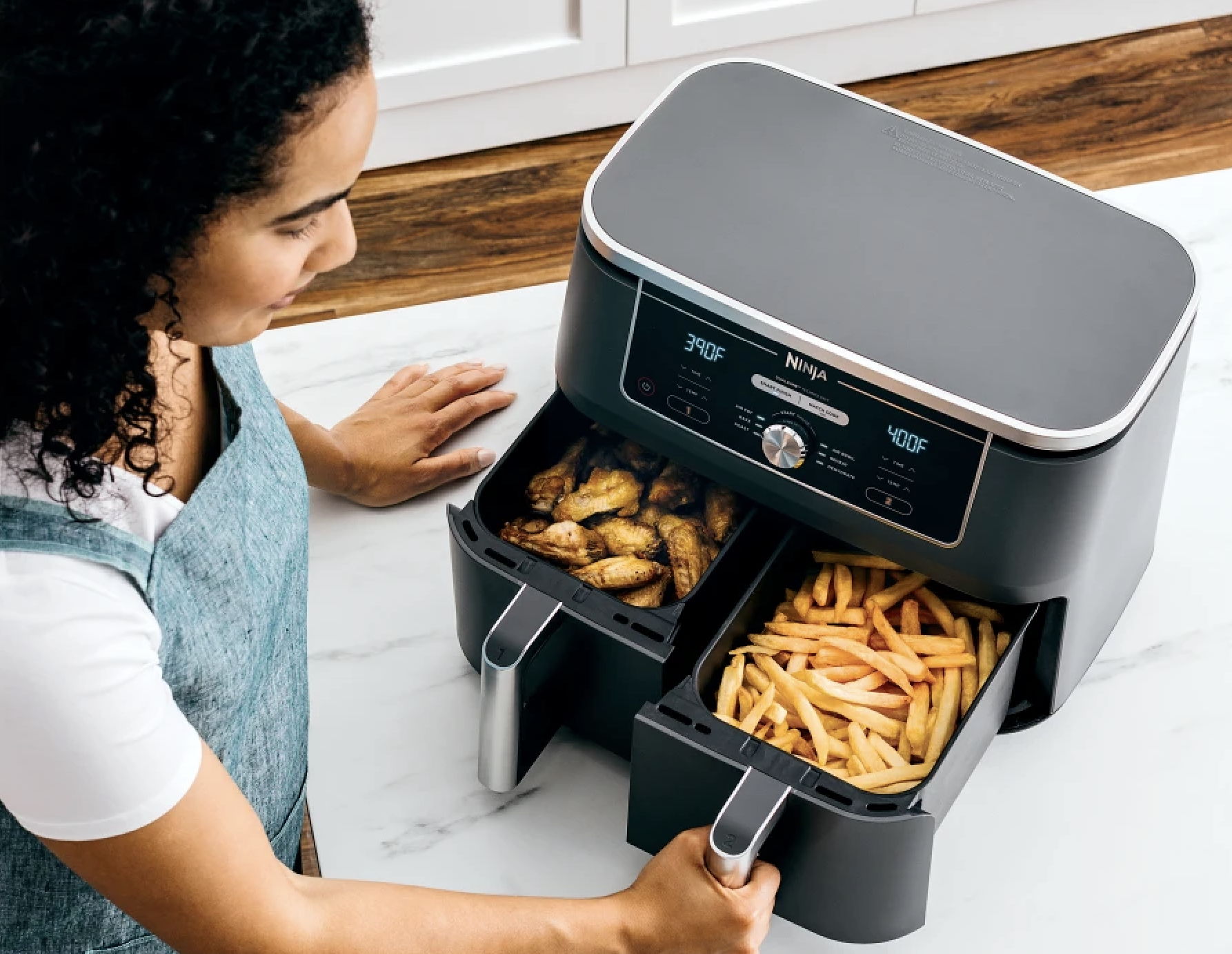 The air fryer with chicken fingers in one basket and fries in the other