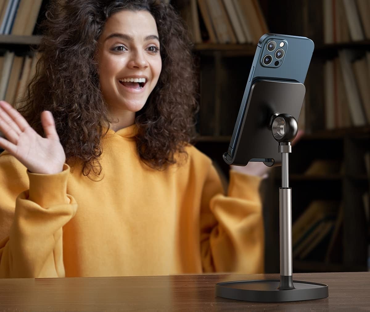 A person video chatting with their phone on a stand on a table in front of them