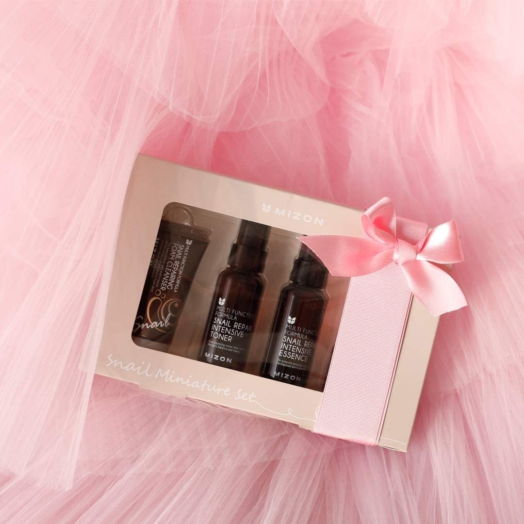 The skincare set in its box on top of tulle, with a ribbon and bow around it