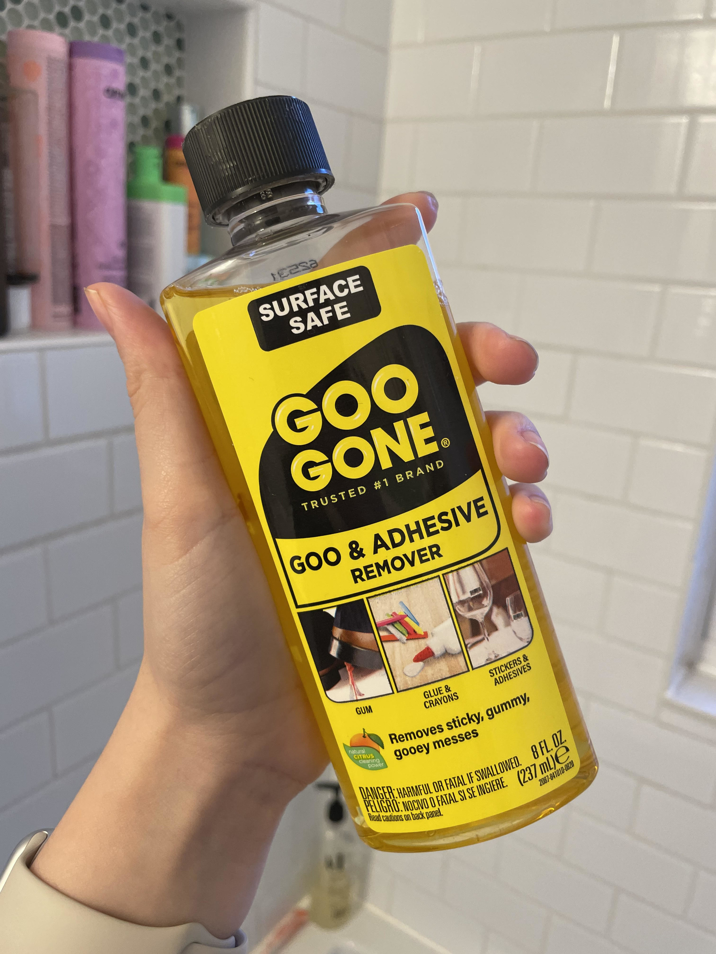 Alice holding up a bottle of Goo Gone in her shower