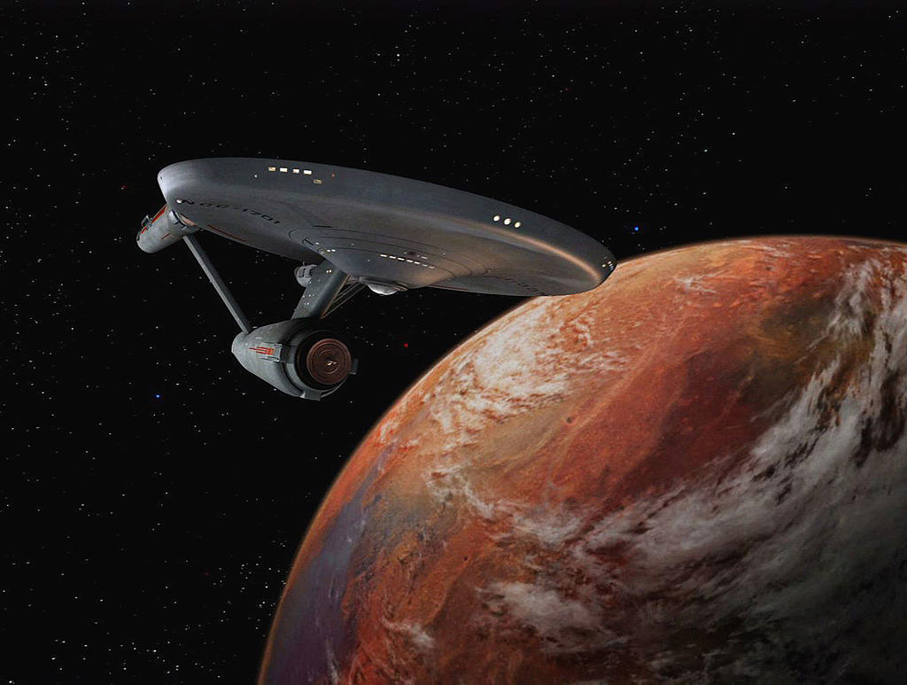 the starship enterprise flying over a red planet