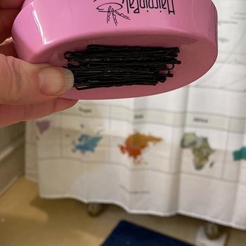 reviewer holding the bobby pin tray upside down, and all of the pins are held tightly in place