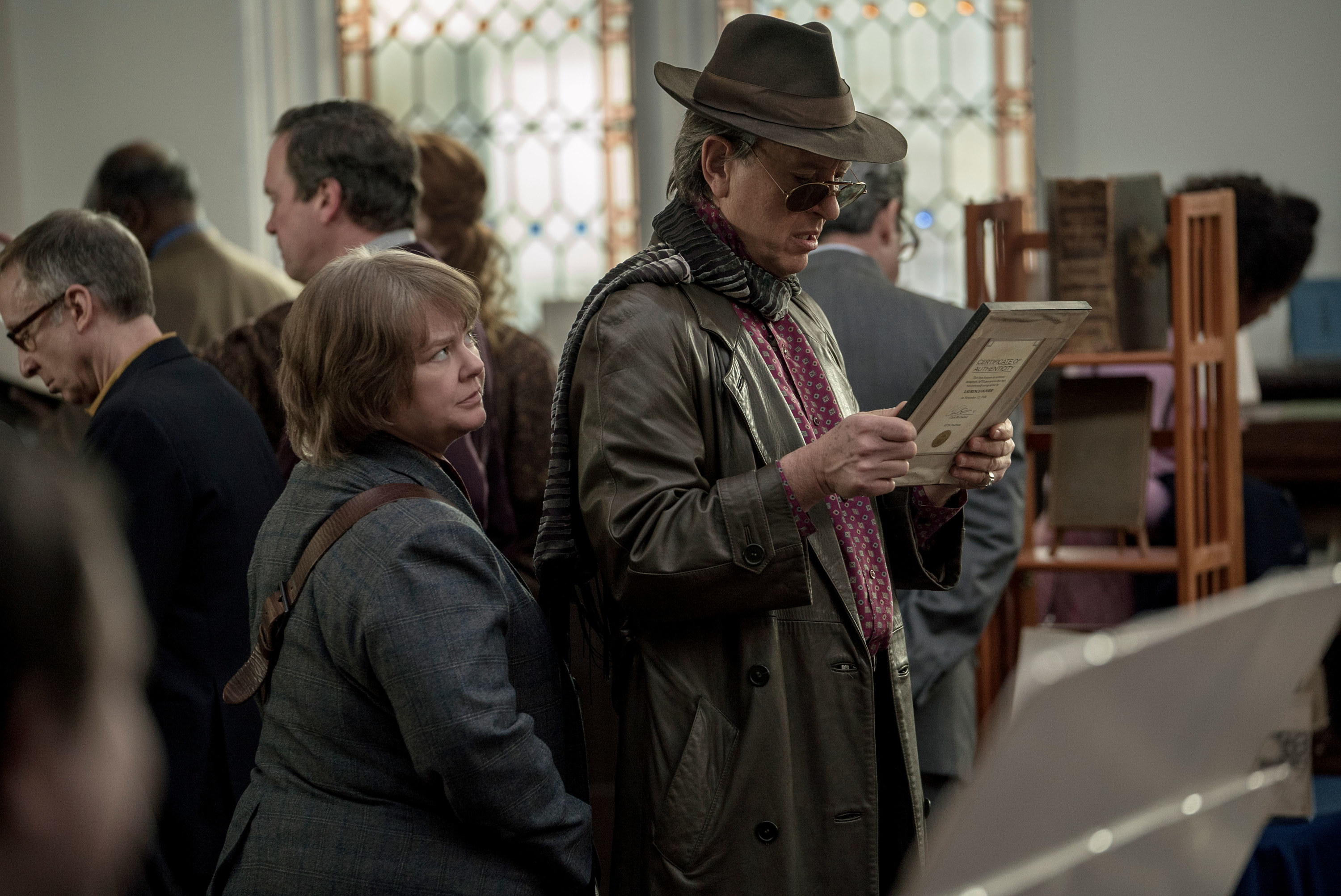 Melissa McCarthy and Richard E. Grant look at an old book