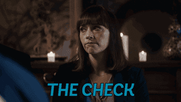 Rashida Jones as Angie Tribeca sits at a table and waves her hand as she says &quot;The check&quot; in &quot;Angie Tribeca&quot;