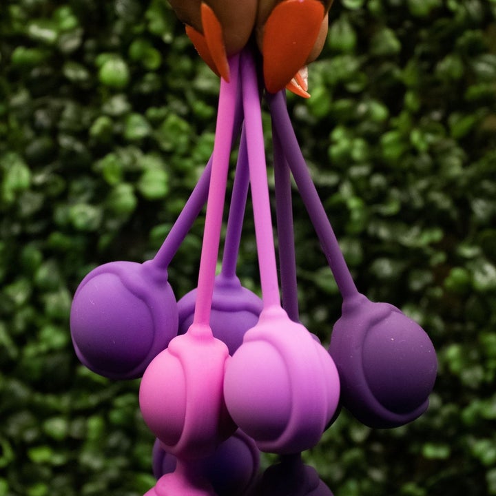 Model holding pink and purple kegel weights