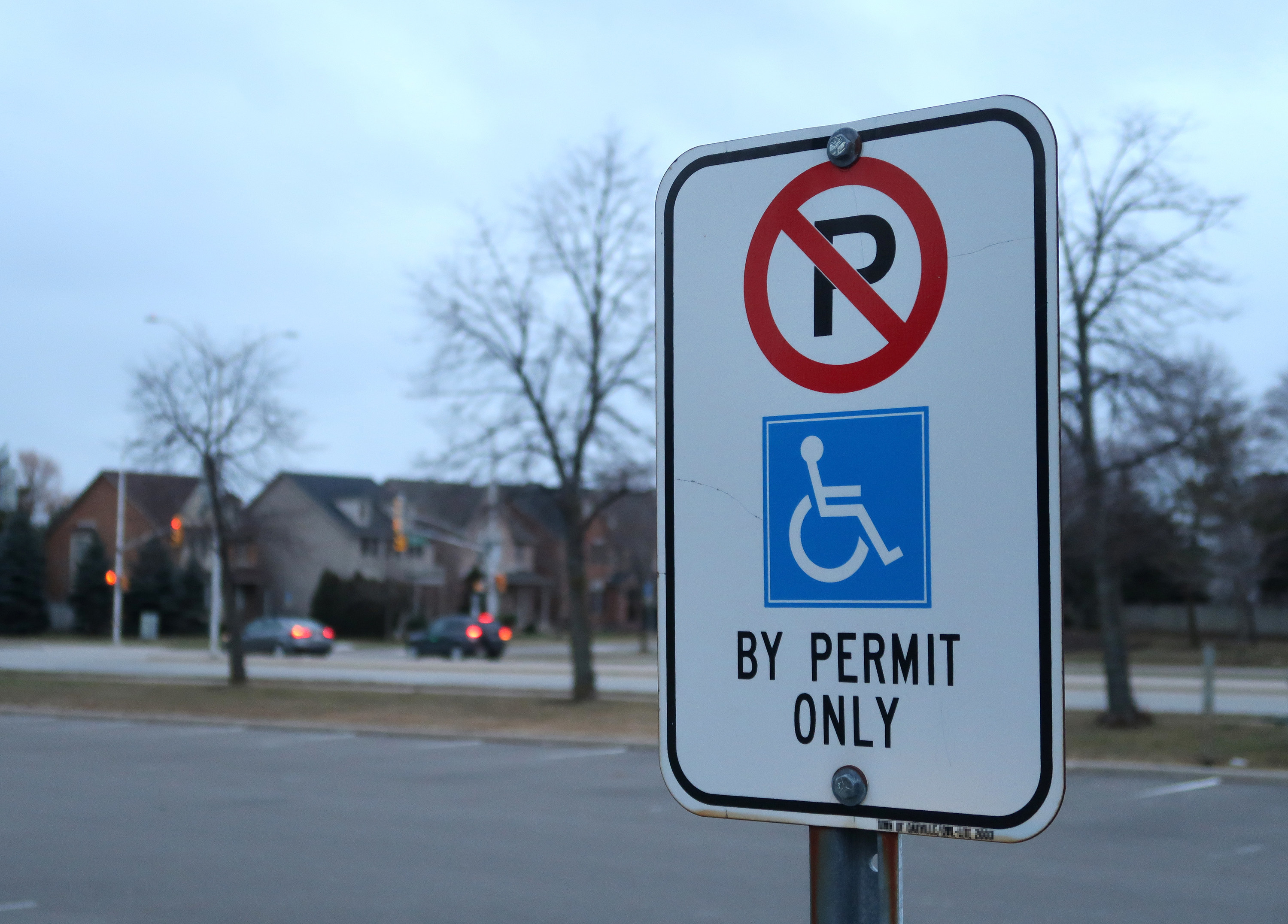 A sign outside that says &quot;No parking by permit online&quot; with a handicapped image