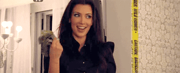 Kim Kardashian fanning herself with money