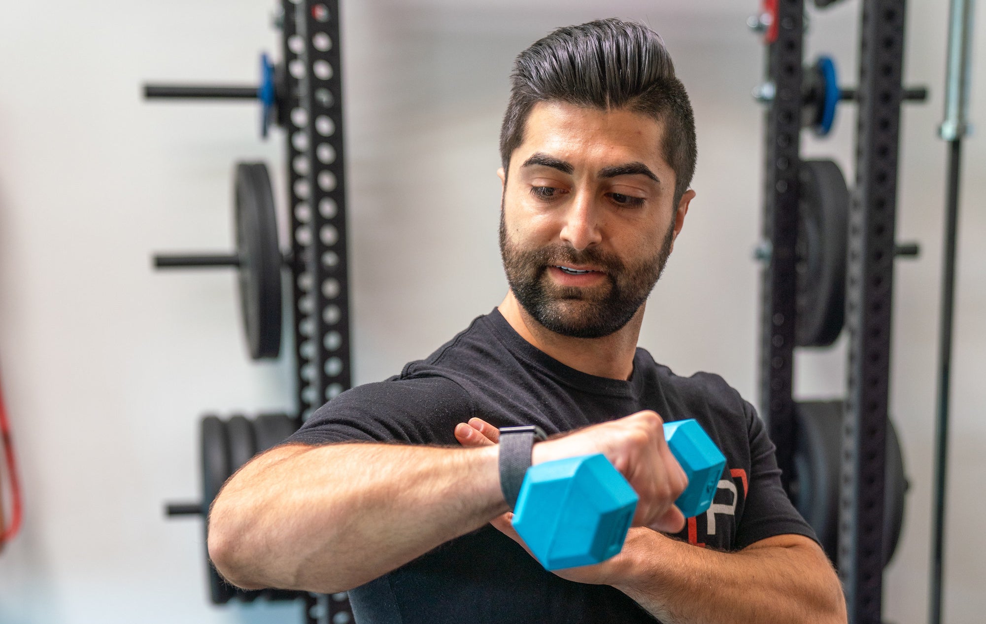 Dr. Arash Maghsoodi performs a shoulder exercise with a weight while holding his shoulder