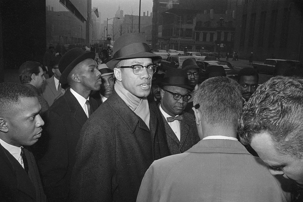 Malcolm X walks down a street with members of the Nation.