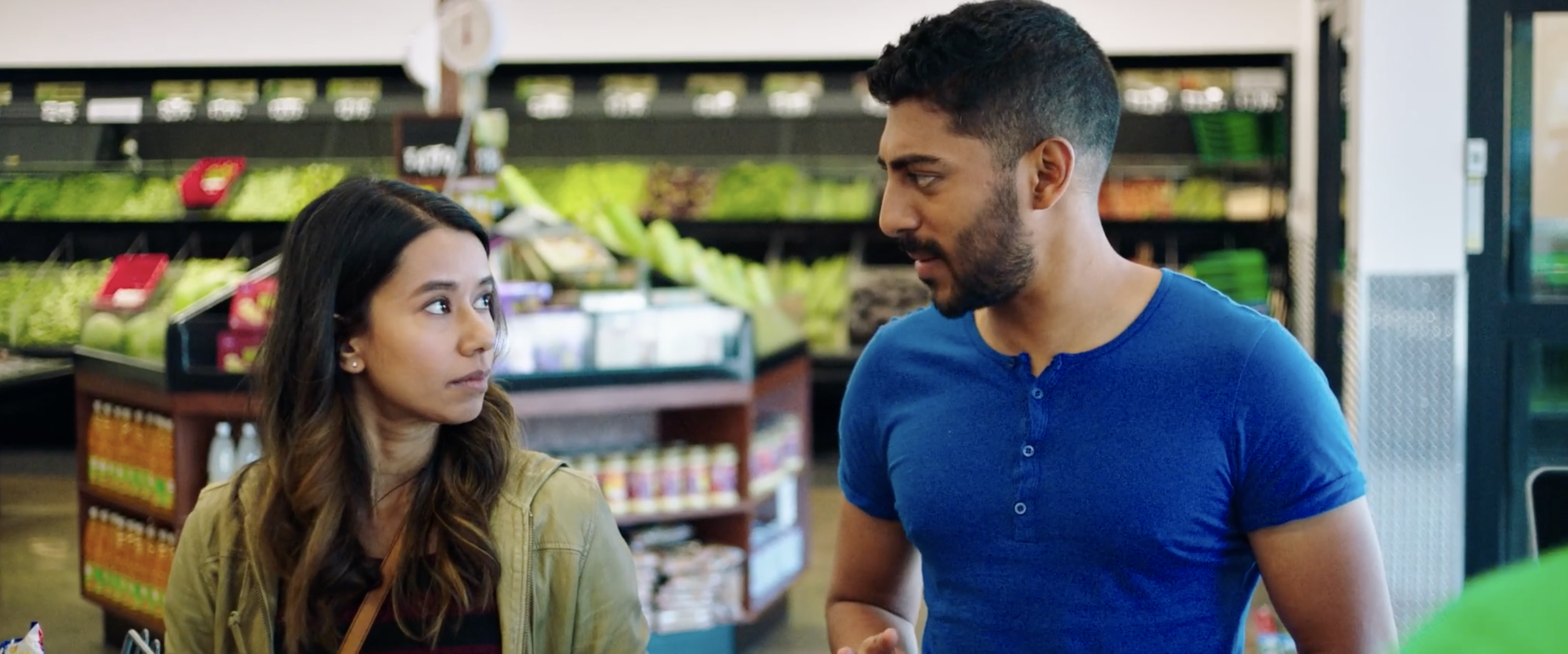 Monica and Sonny looking at one another in a grocery store