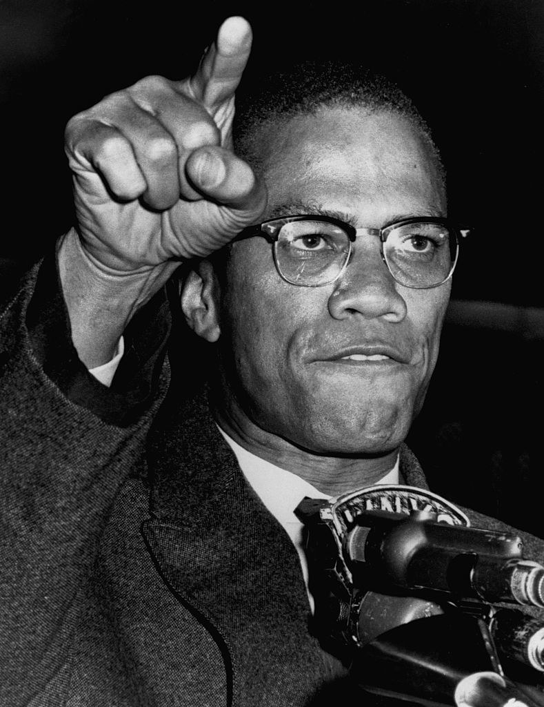 Malcolm X angrily speaks to the press and points