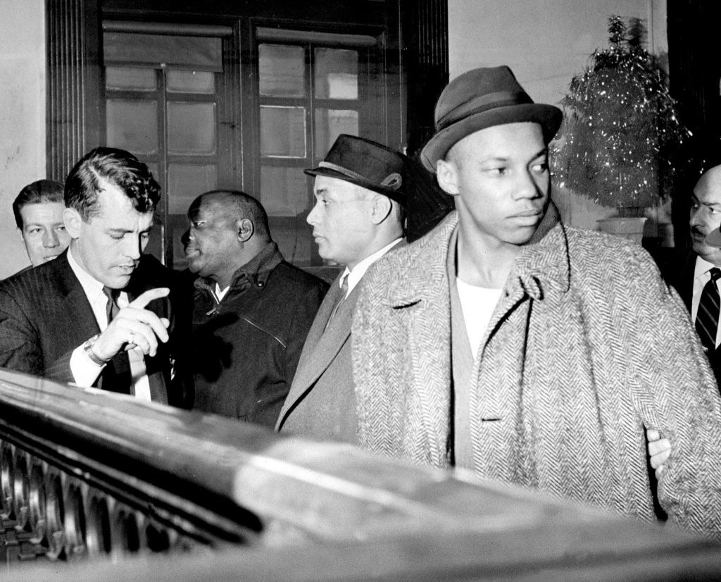 A detective talks to Black muslims William Gaines (left), Thomas 15X Johnson (center), and Norman 3X Butler (right)