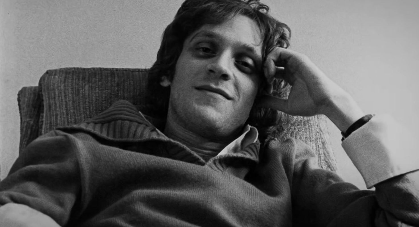 Howard Ashman sits on a chair and smiles in a photo shown in the Disney + documentary, &quot;Howard&quot;