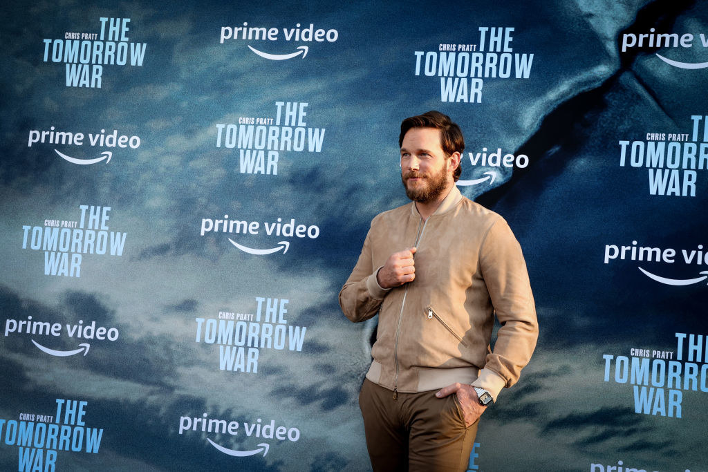 Chris Pratt dressed casually in front of The Tomorrow War posters