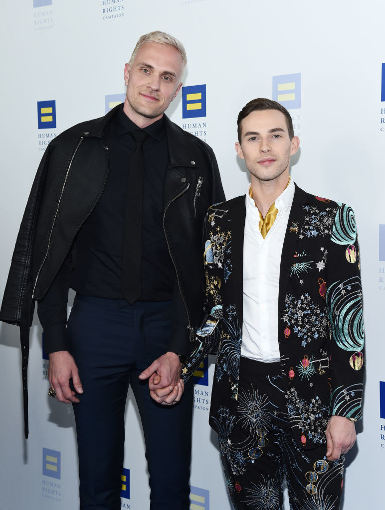 Jussi and Adam hold hands on the carpet of a Human Rights Campaign event