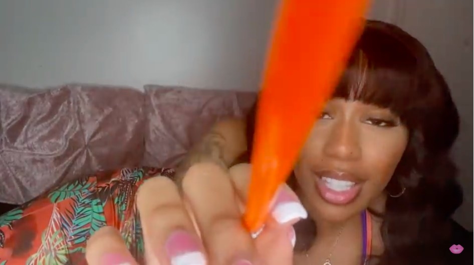 Triniti J纳个人关注视频。她指着相机与一个橙色的钢笔/刷她躺在沙发上