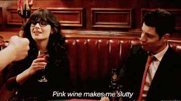 New Girl: Jess is seen with a glass of wine putting it towards her lips, and Winston is on the right looking her way