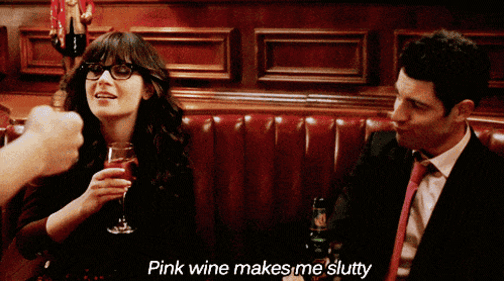 New Girl: Jess is seen with a glass of wine putting it towards her lips, and Winston is on the right looking her way