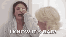 woman holding a pad to her eye and saying &quot;I know it&#x27;s bad!&quot; to another woman