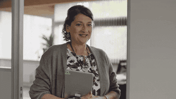 Woman excitedly holding up an iPad