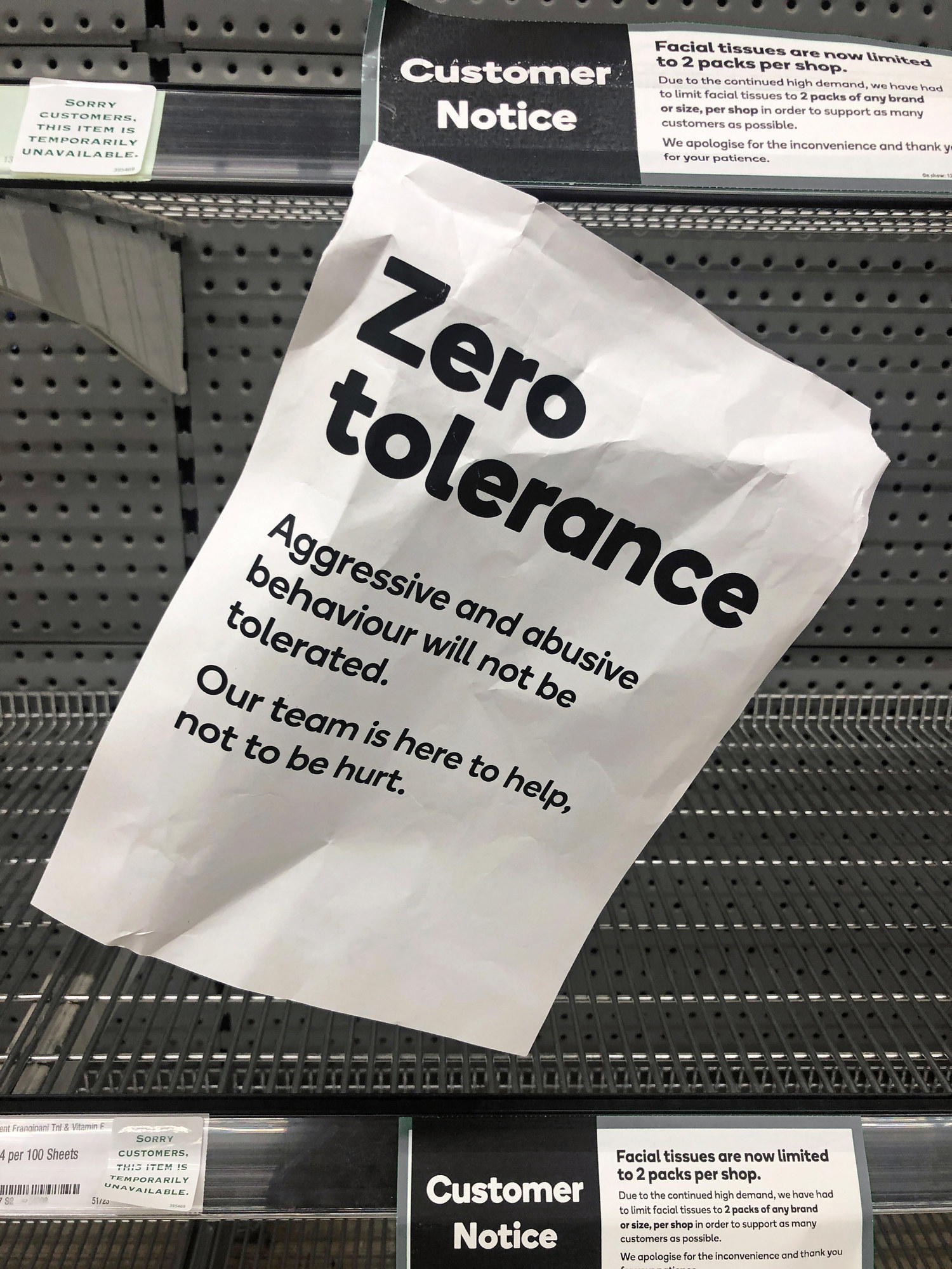 A crumpled paper sign alerting supermarket customers that aggressive and abusive behaviour will not be tolerated