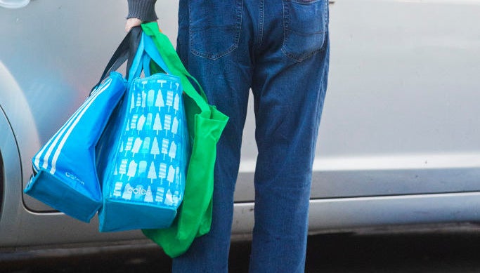 A man holding reusable shopping bags