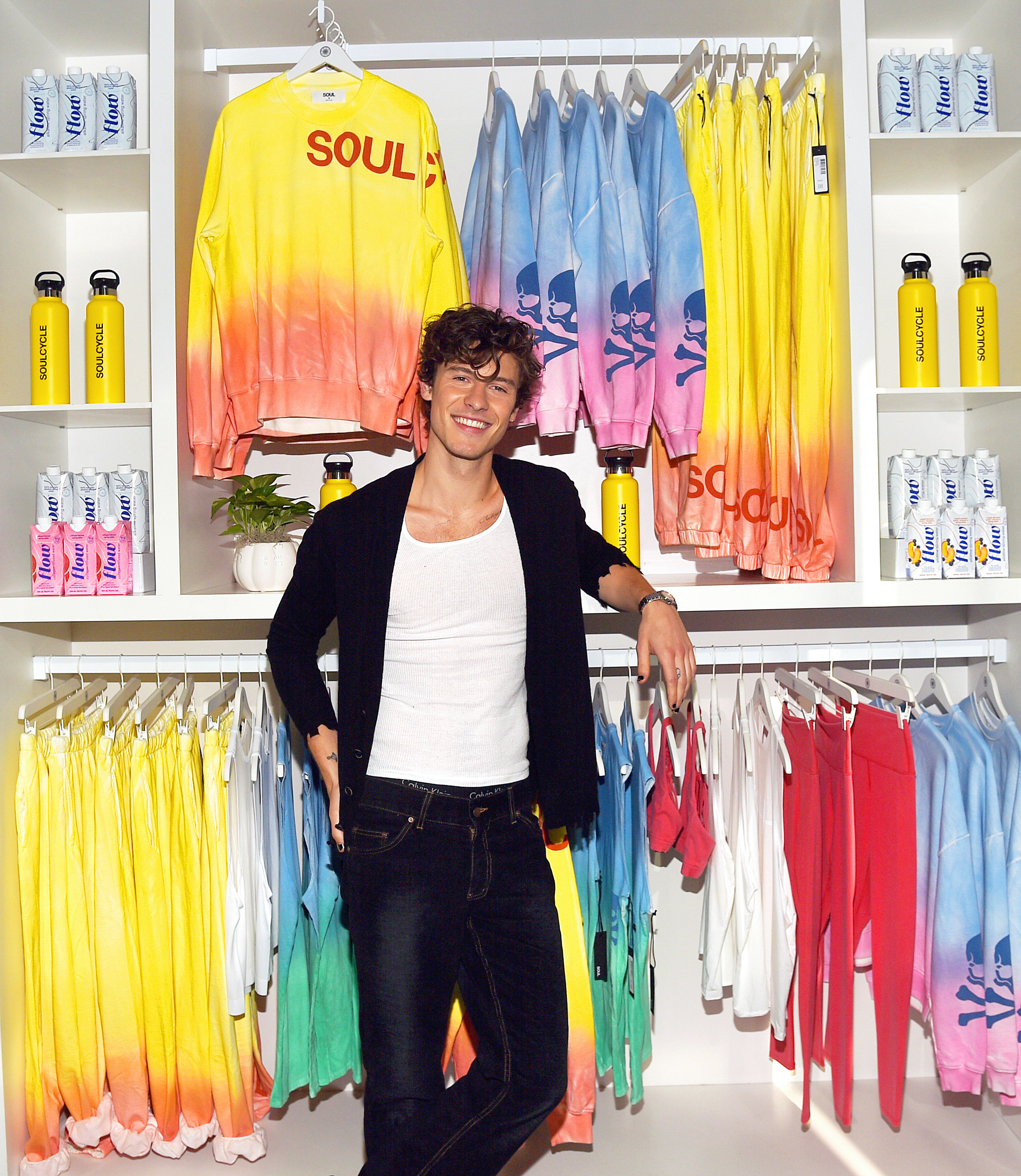 Mendes poses for a photo in front of a colorful set of clothes