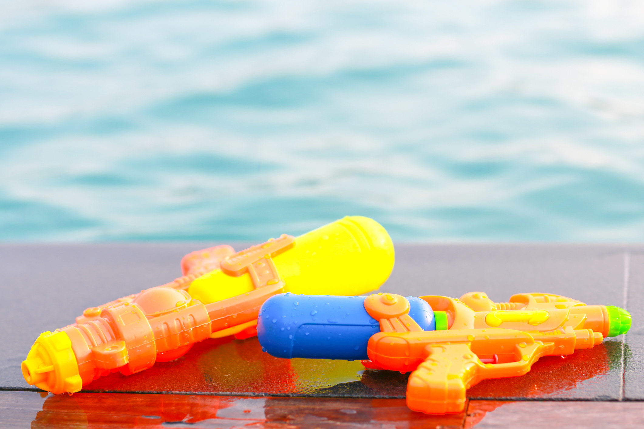 Colorful kids&#x27; water guns near a pool