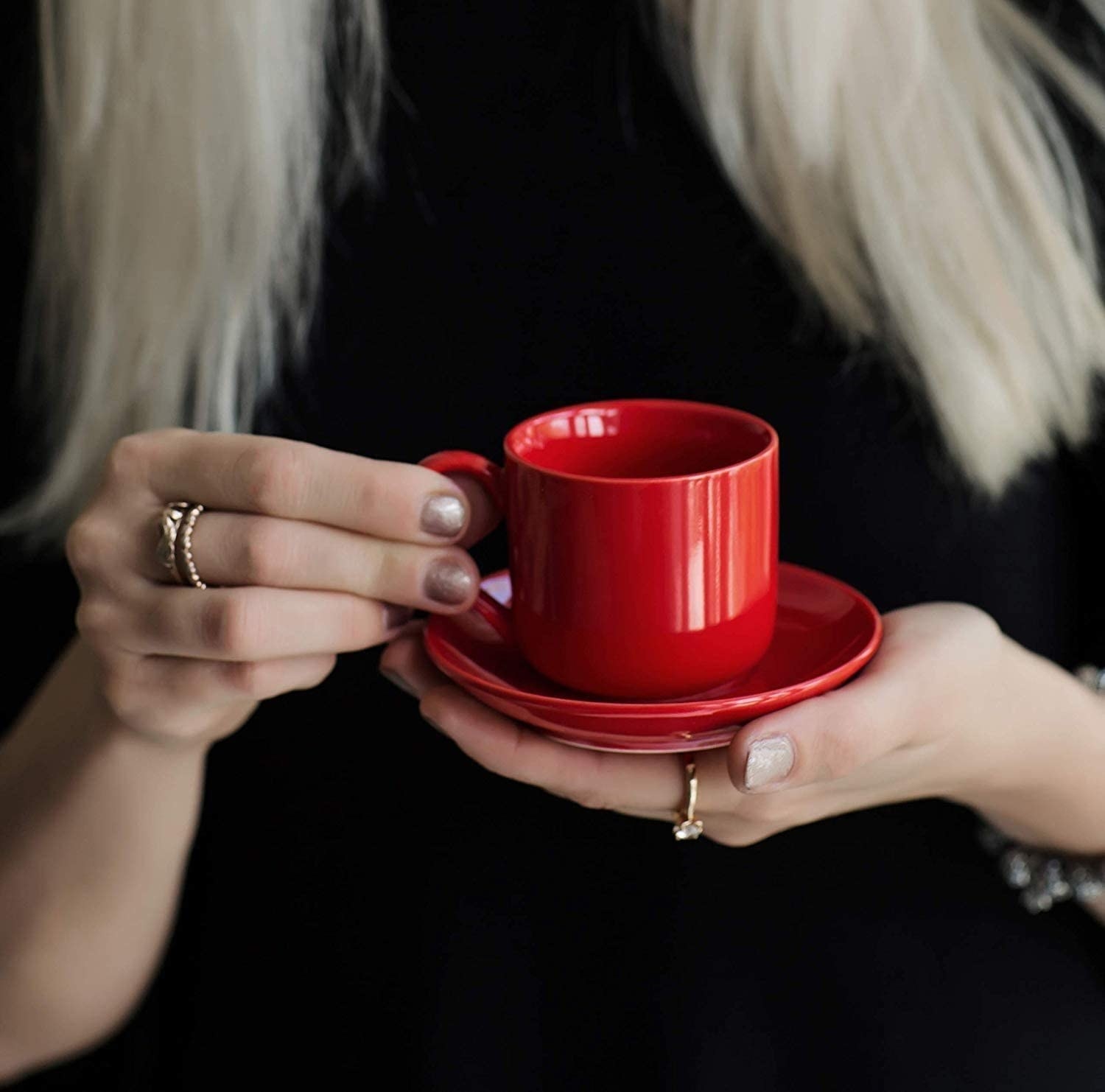 A person holding the mug on a saucer