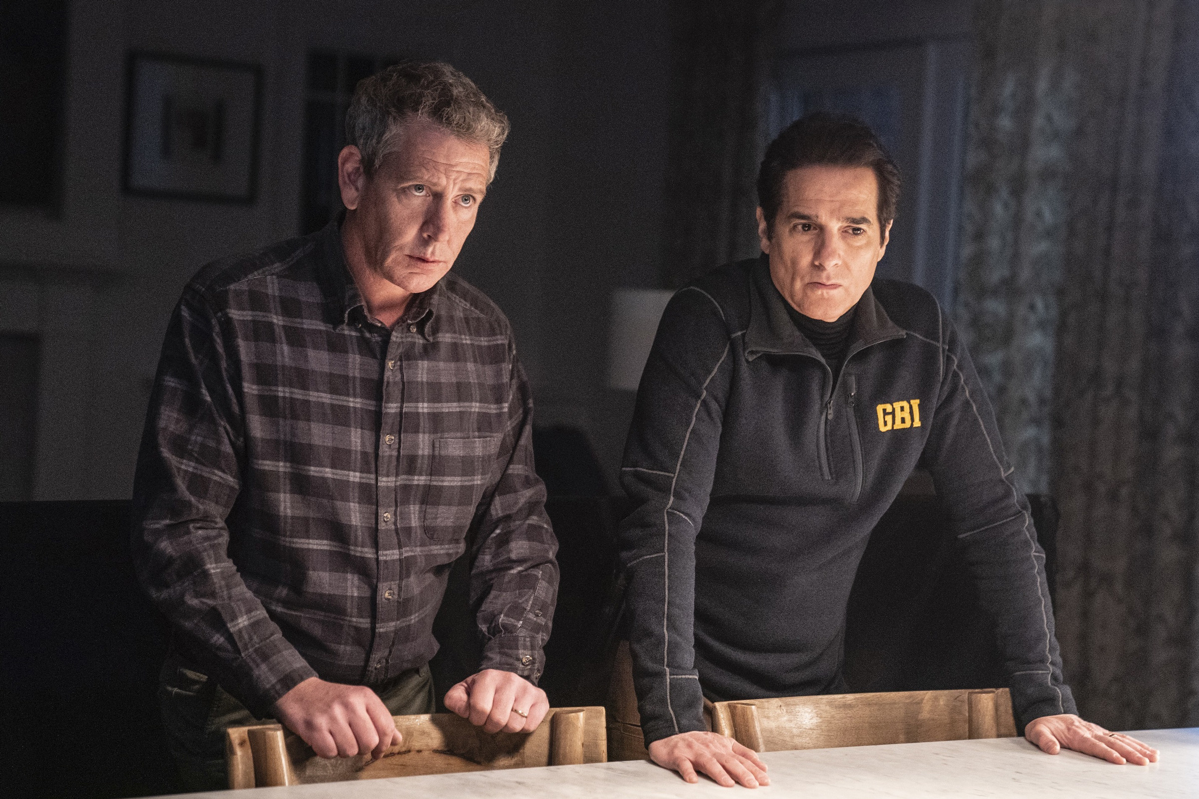 Ben Mendelsohn as detective Ralph Anderson and Yul Vazquez as Yuni Sablo stood over a dining table in &quot;The Outsider&quot;