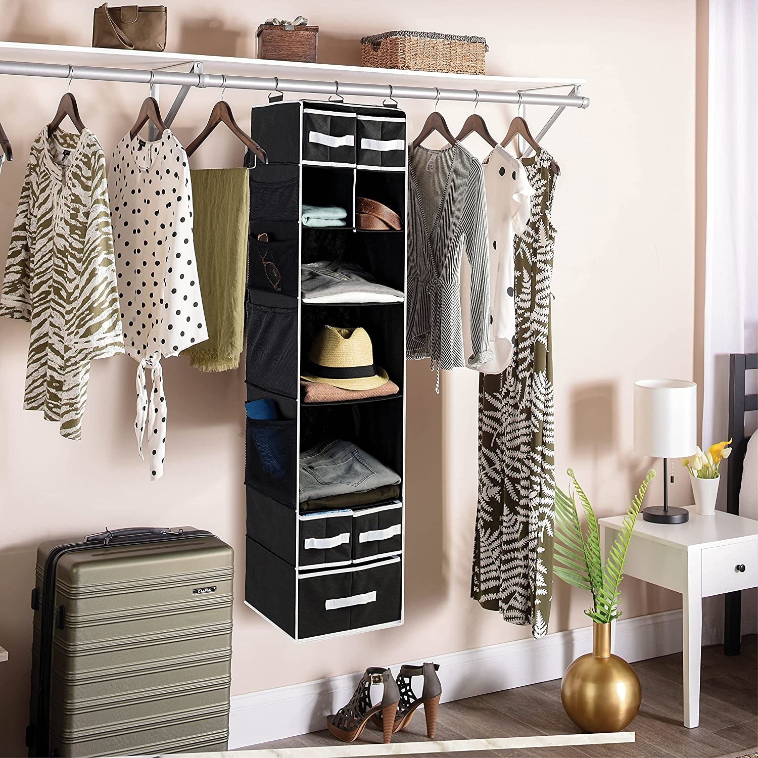 The filled organizer hanging on a closet rod between rows of shirts and dresses