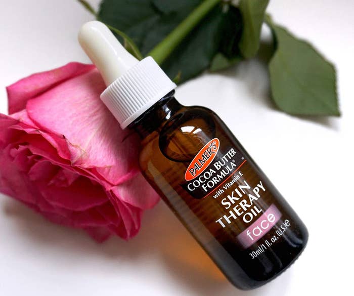 Bottle of the skin therapy oil laying on a rose