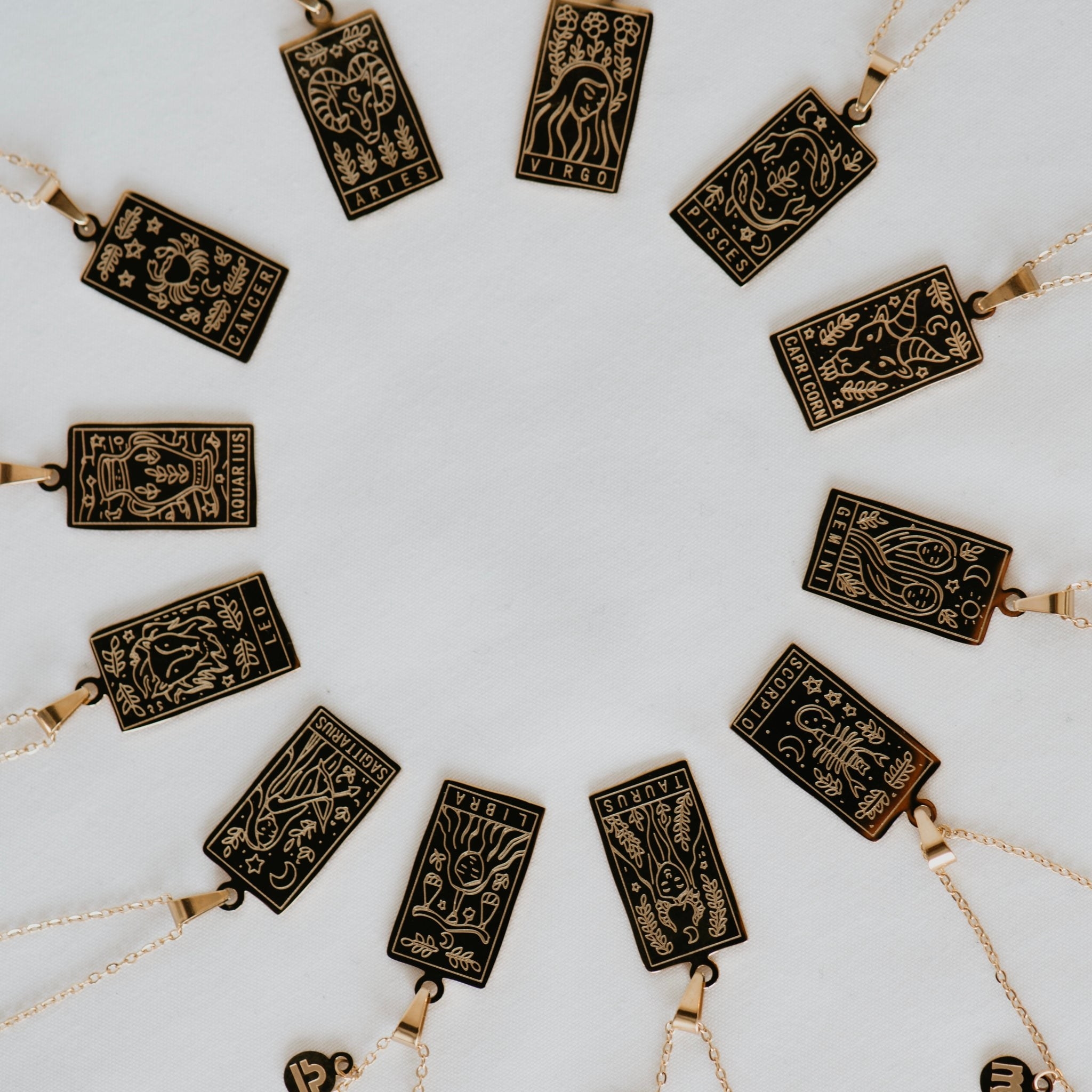 a circle of necklaces with rectangular charms that each depict a zodiac sign