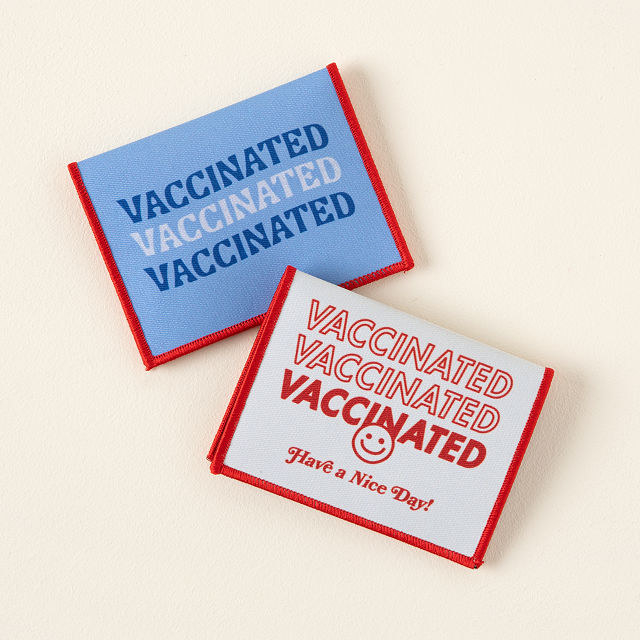 Two card holders in blue and white reading &quot;vaccinated&quot; in various designs