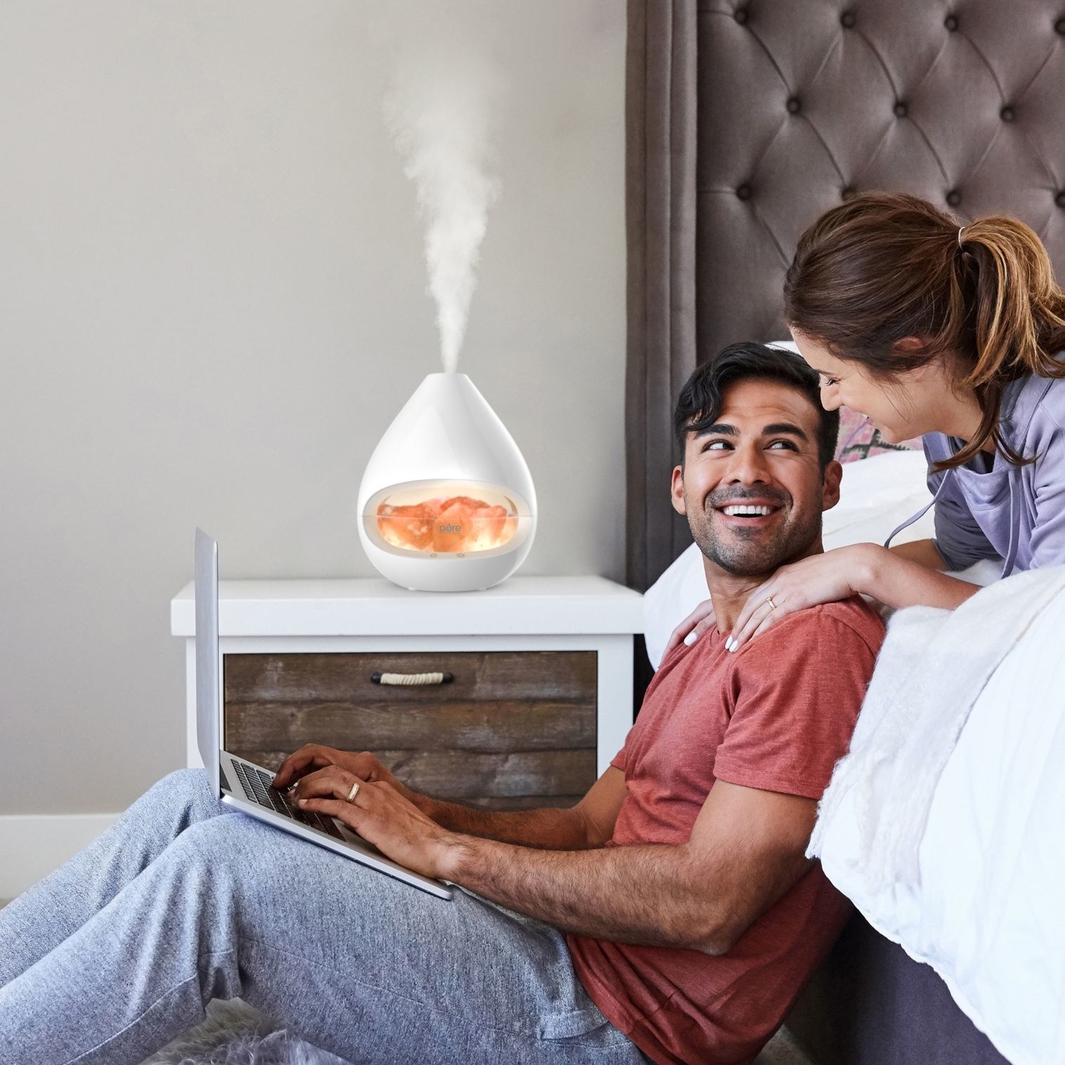 Models in a bedroom with a crystal salt lamp diffuser atop a nightstand