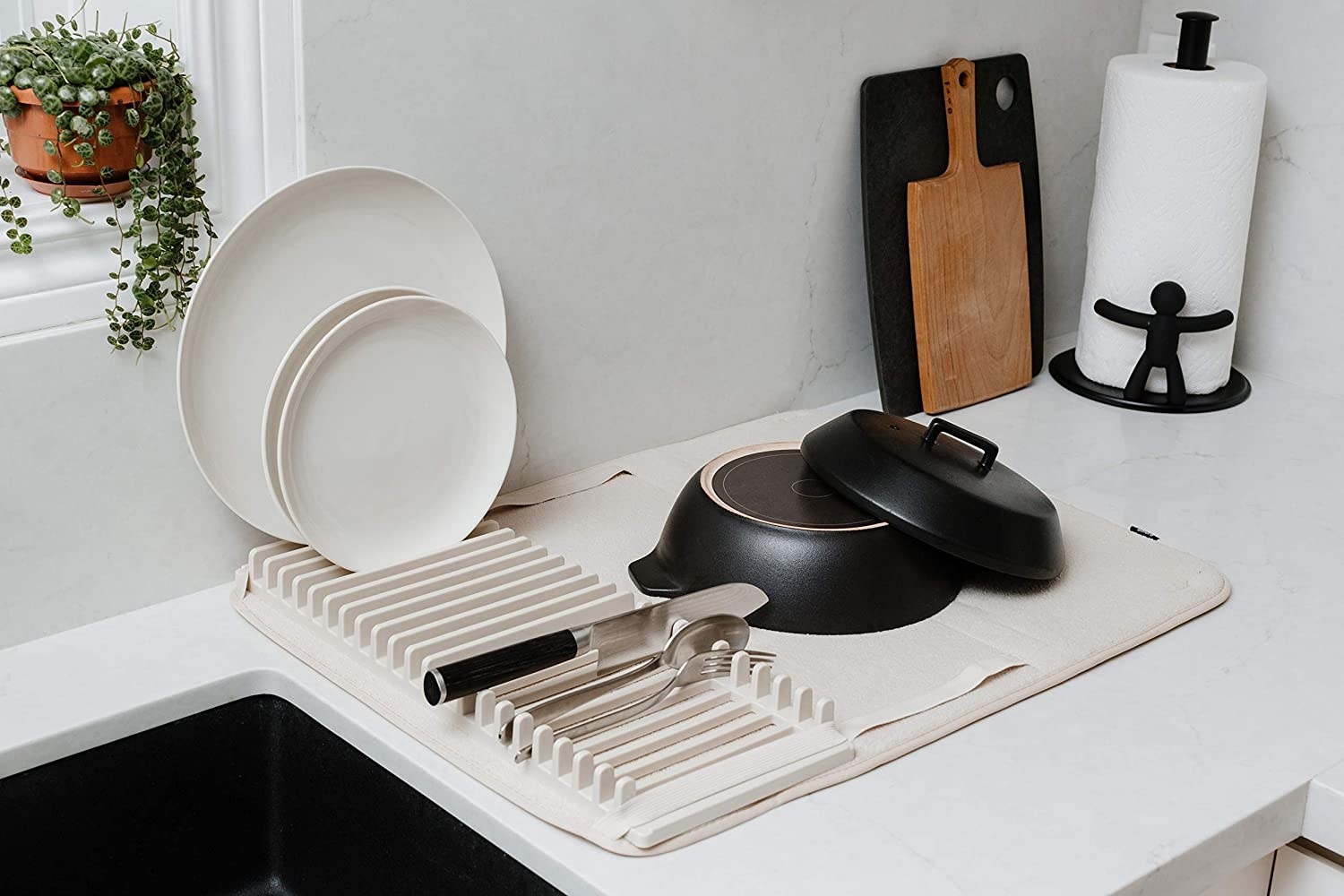 The dish mat on a counter with several pots, pans, and dishes on it